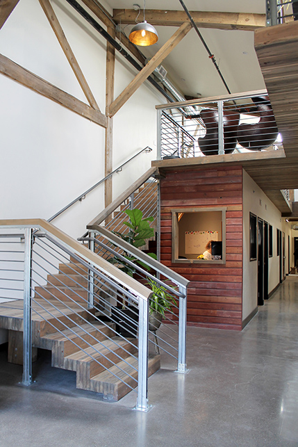 Looking up to the mezzanine conference room, nail laminated staircase, a reception desk features original Box factory siding